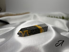 Treasured Energies Bumblebee Jasper crystal tower with vibrant yellow and black volcanic layers on white satin fabric