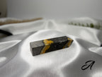 Treasured Energies Bumblebee Jasper crystal tower with vibrant yellow and black volcanic patterns on satin fabric.