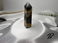 Treasured Energies Bumblebee Jasper crystal tower with black, yellow, and grey banded patterns on a silk background.