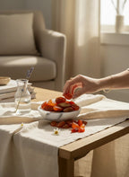 Treasured Energies polished carnelian stone tumbled gemstones in a marble bowl on a linen-covered table with a hand reaching in.