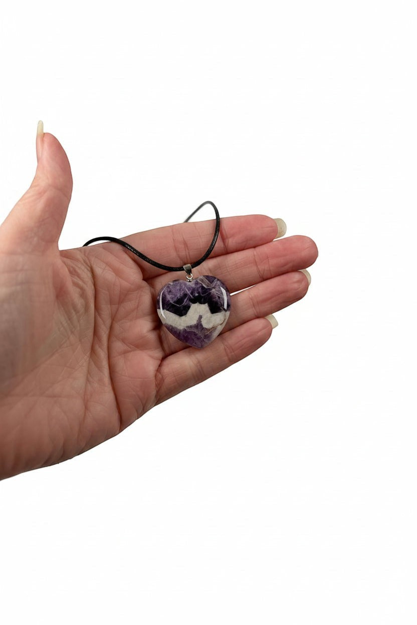 Treasured Energies heart-shaped chevron amethyst pendant necklace with purple and white bands held in a hand