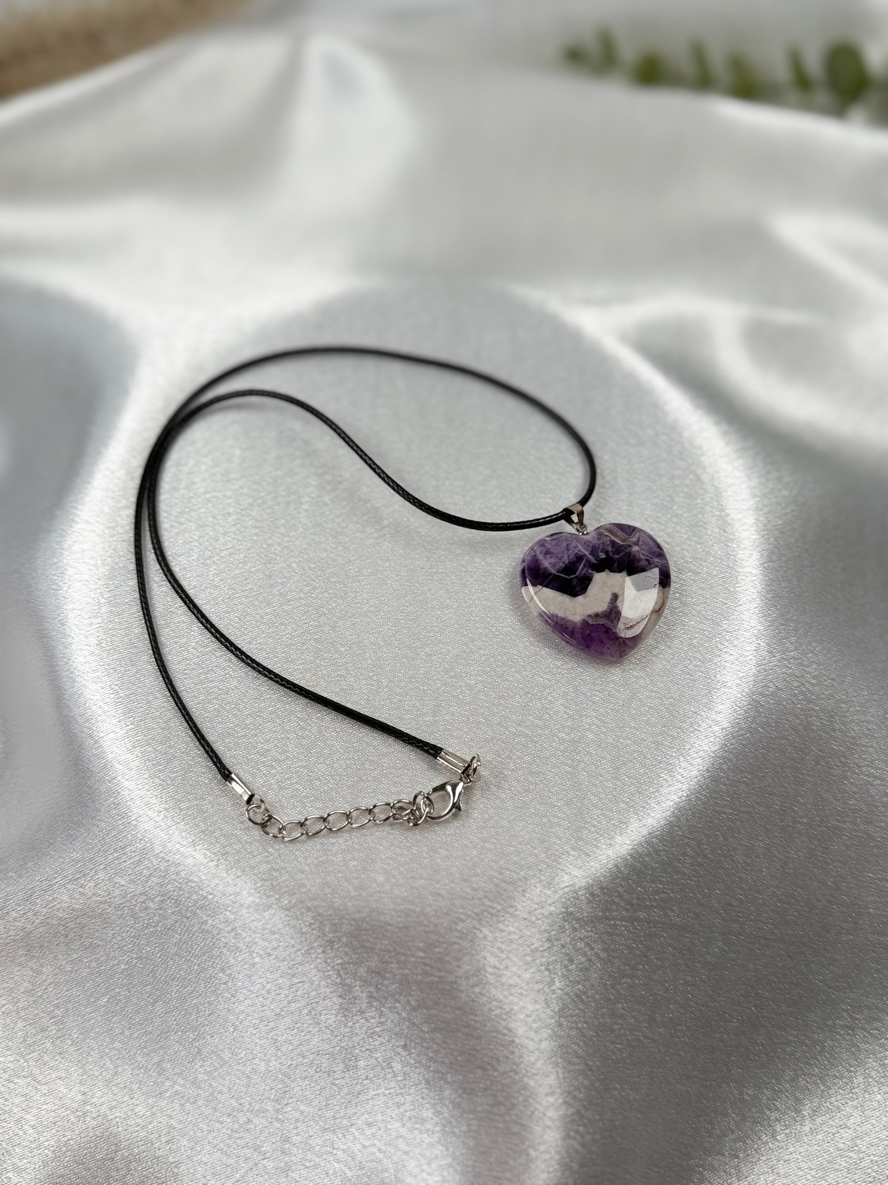 Treasured Energies heart-shaped chevron amethyst pendant necklace with purple and white bands on a black cord.