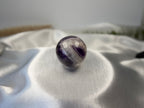 Treasured Energies polished Chevron Amethyst crystal sphere featuring deep purple and white V-shaped bands on satin.
