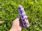 Treasured Energies Chevron Amethyst crystal tower held in hand, showing deep purple and white V-shaped bands.