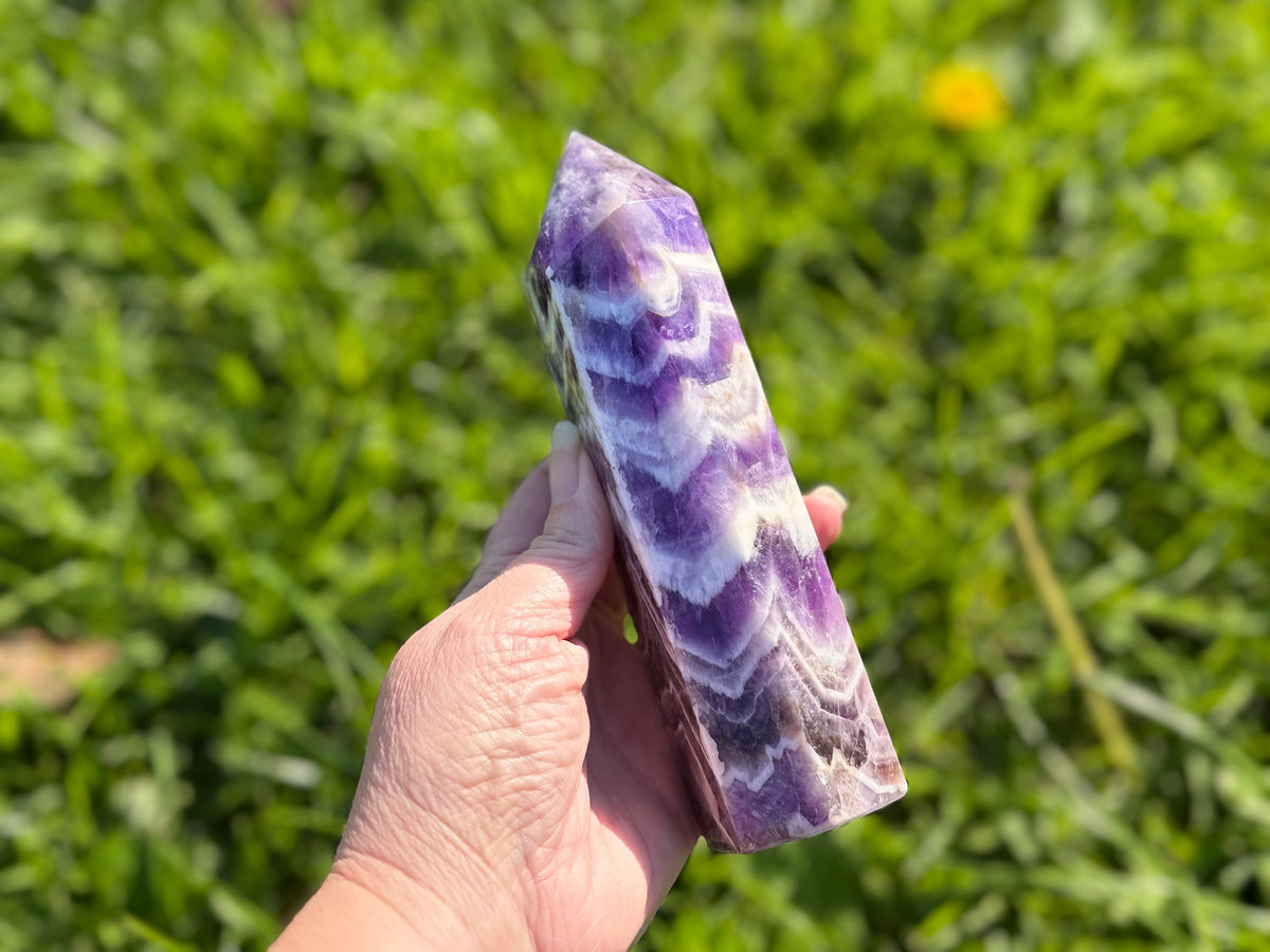 Treasured Energies Chevron Amethyst crystal tower held in hand, showing deep purple and white V-shaped bands.