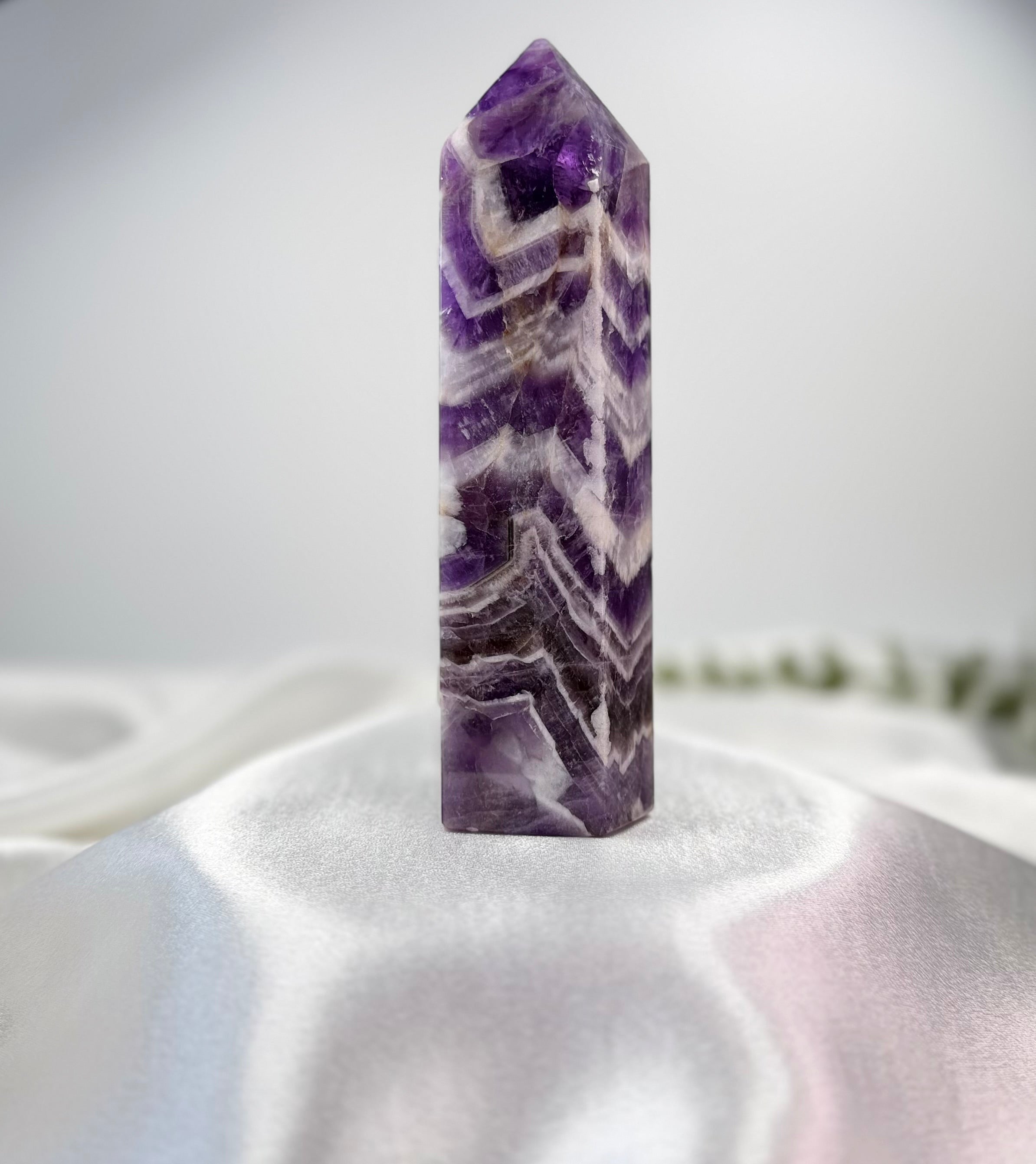 Treasured Energies Chevron Amethyst crystal tower with deep purple and white V-shaped bands on a white silk background.