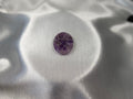 Treasured Energies Chevron Amethyst worry stone with purple and white V-shaped bands on a smooth white satin background.