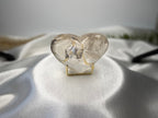 Treasured Energies clear quartz heart crystal with visible phantom inclusions displayed on a gold wire stand.