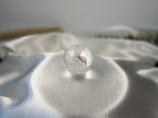 Treasured Energies clear quartz sphere with visible phantom inclusions resting on a smooth white satin fabric.