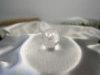 Treasured Energies clear quartz crystal sphere with visible phantom inclusions resting on white satin fabric.