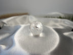 Treasured Energies clear quartz crystal sphere with visible phantom inclusions resting on a white satin fabric background