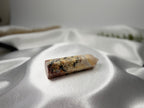 Treasured Energies Crazy Lace Agate crystal tower with intricate swirling patterns on a white satin fabric background.