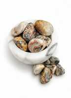 Treasured Energies tumbled Crazy Lace Agate stones with intricate swirling patterns in a white marble bowl.
