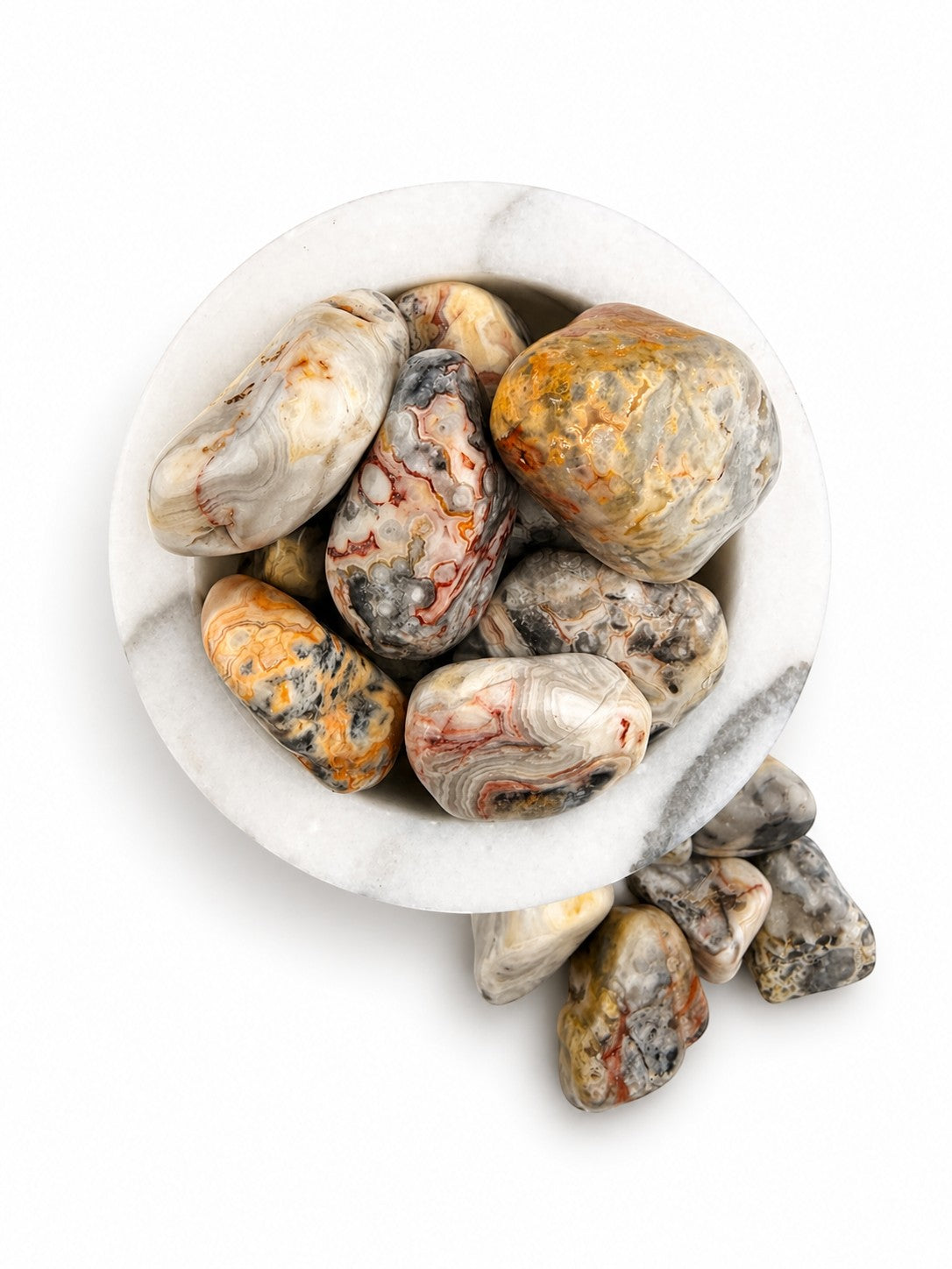 Treasured Energies tumbled Crazy Lace Agate stones with intricate swirling patterns in a white marble bowl.