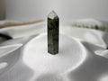 Treasured Energies Dragon Blood Jasper crystal tower with green and red patterns on a white satin background.