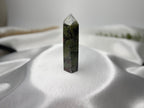 Treasured Energies Dragon Blood Jasper crystal tower with green and red patterns on a white satin background.