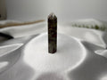 Treasured Energies Dragons Blood Jasper crystal tower with green and red patterns on a white satin background.
