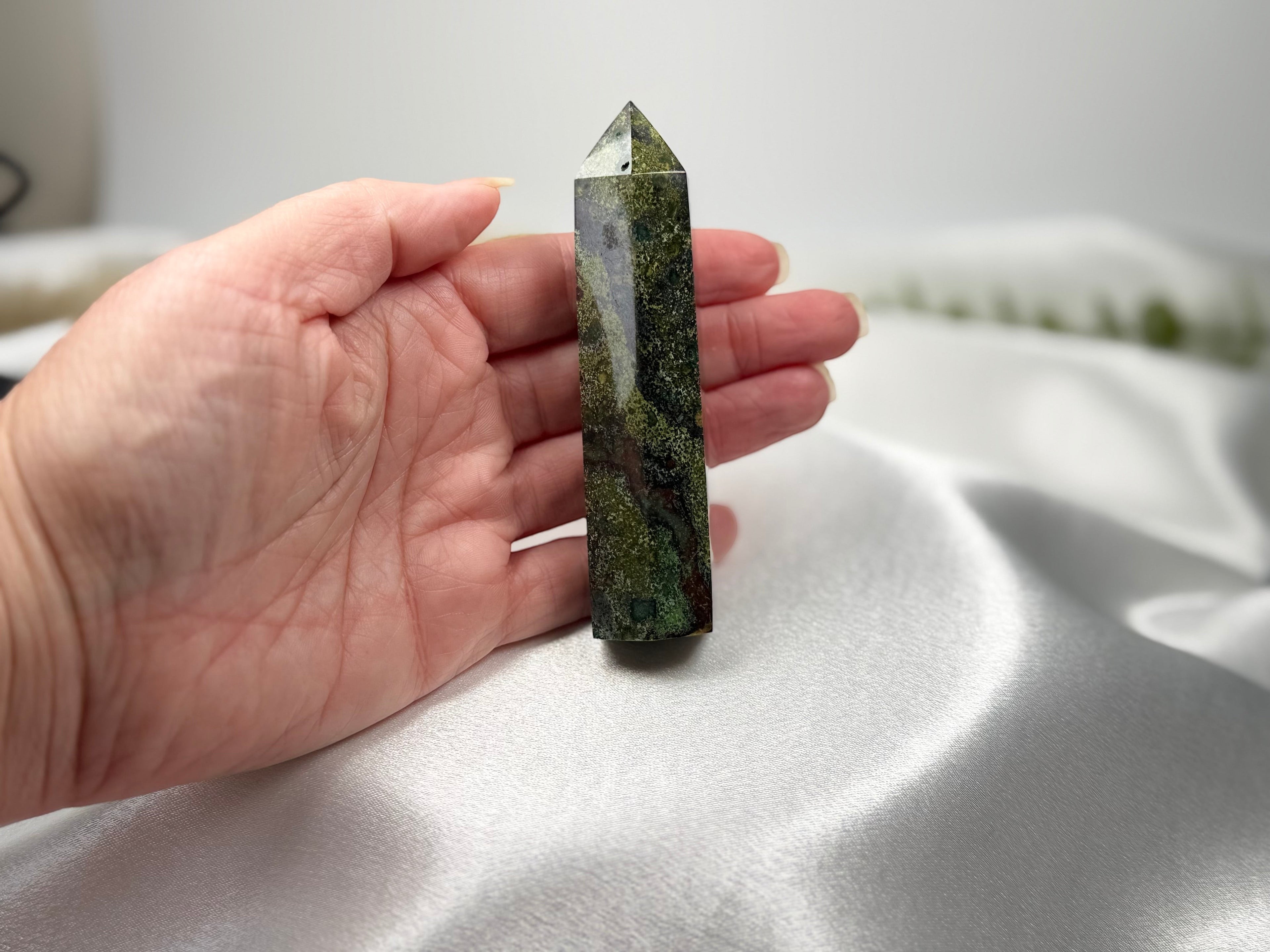Treasured Energies Dragons Blood Jasper crystal tower held in a hand, showing green and red stone patterns.