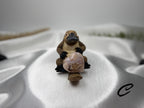 Treasured Energies flower agate crystal heart held by a small platypus figurine on a white satin background.