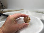 Treasured Energies polished flower agate crystal heart held in hand, showcasing natural floral inclusions and warm tones.