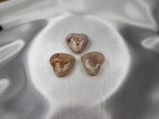 Treasured Energies polished flower agate crystal hearts with floral inclusions on a soft white satin background
