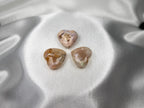 Treasured Energies flower agate crystal hearts with floral inclusions on a soft white satin background.