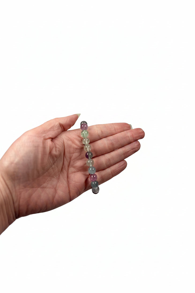 Treasured Energies fluorite gemstone beaded stretch bracelet held in a hand against a white satin background