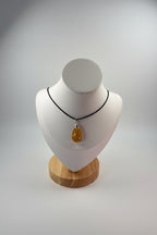 Treasured Energies golden healer quartz teardrop pendant necklace on a black cord displayed on a white mannequin bust.