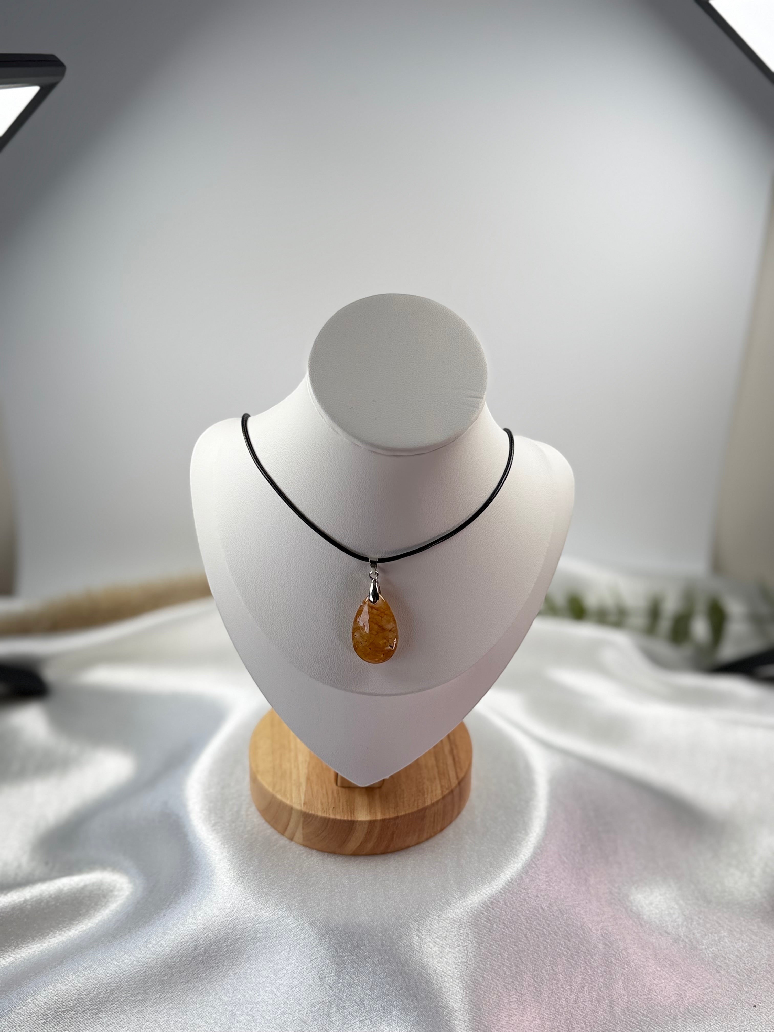 Treasured Energies golden healer quartz teardrop pendant on a black cord necklace displayed on a white bust