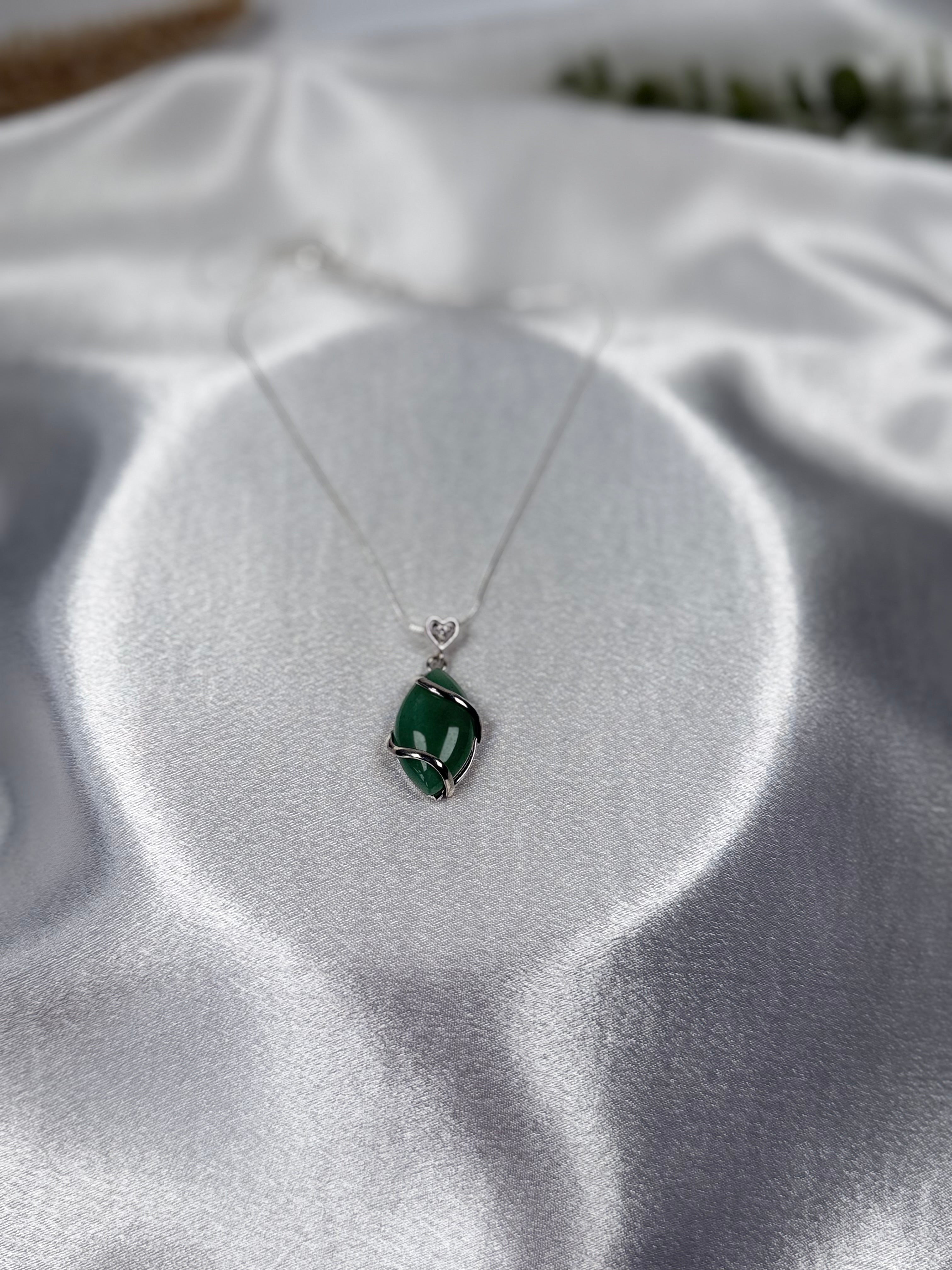 Treasured Energies green aventurine crystal pendant necklace with a silver swirl setting on a white satin background