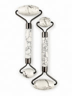 Treasured Energies dual-ended facial massage rollers in white Howlite stone with black veining and dark metal hardware.