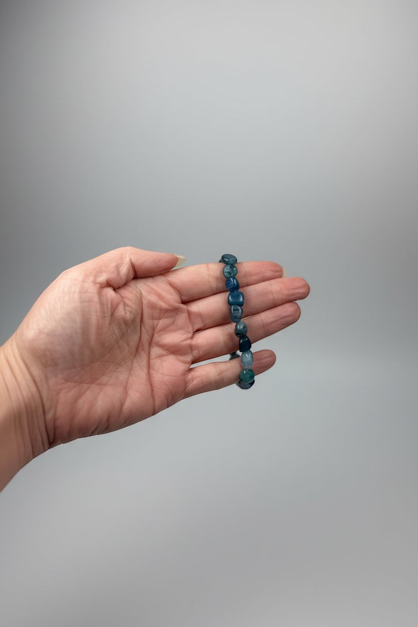 Treasured Energies polished blue kyanite gemstone bead stretch bracelet held in a hand against a neutral background.