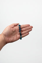 Treasured Energies polished blue kyanite gemstone bead stretch bracelet held in a palm for scale