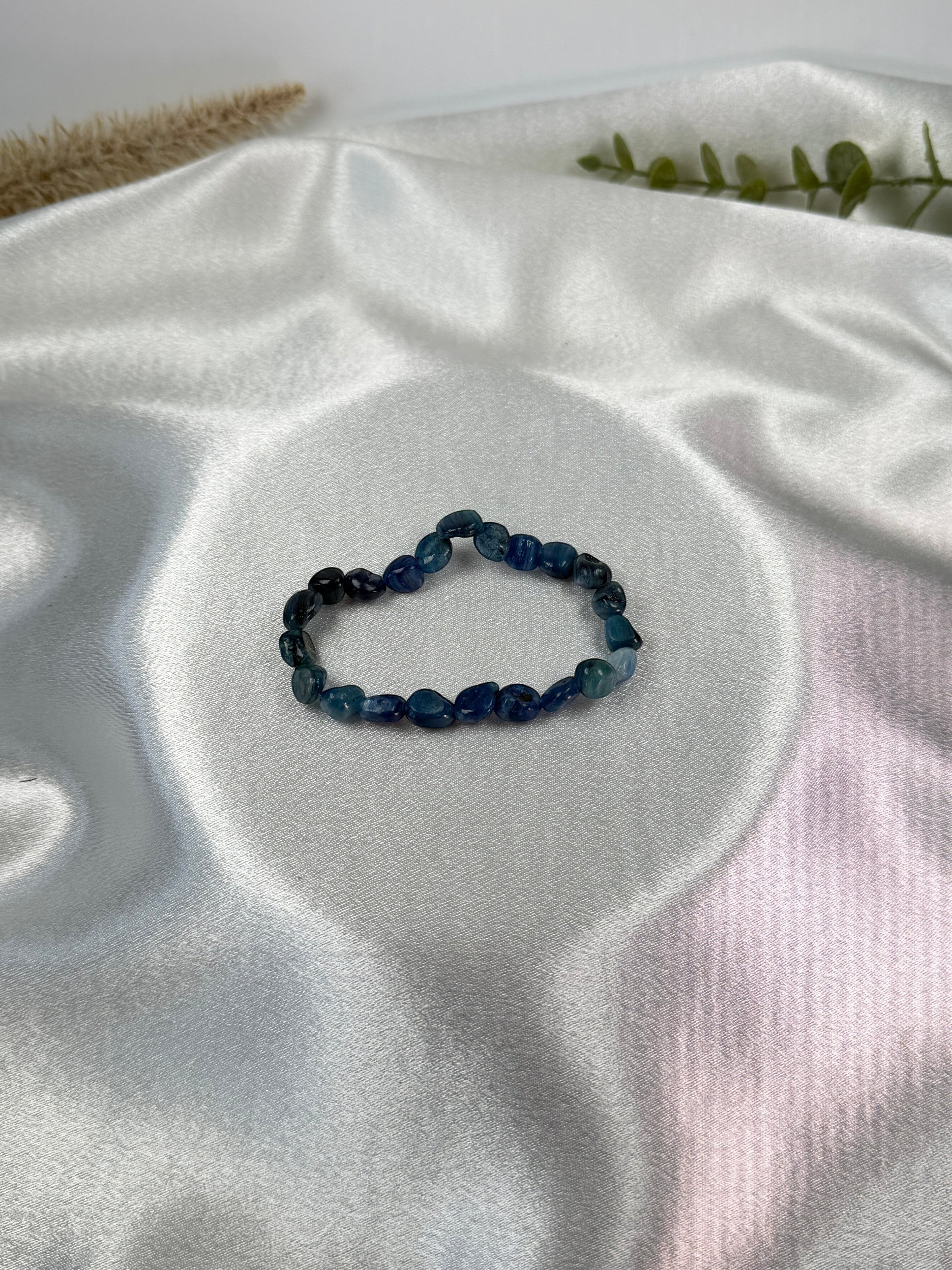 Treasured Energies polished blue kyanite gemstone bead stretch bracelet on a white satin background