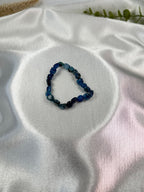 Treasured Energies polished blue kyanite gemstone bead stretch bracelet on a white satin fabric background