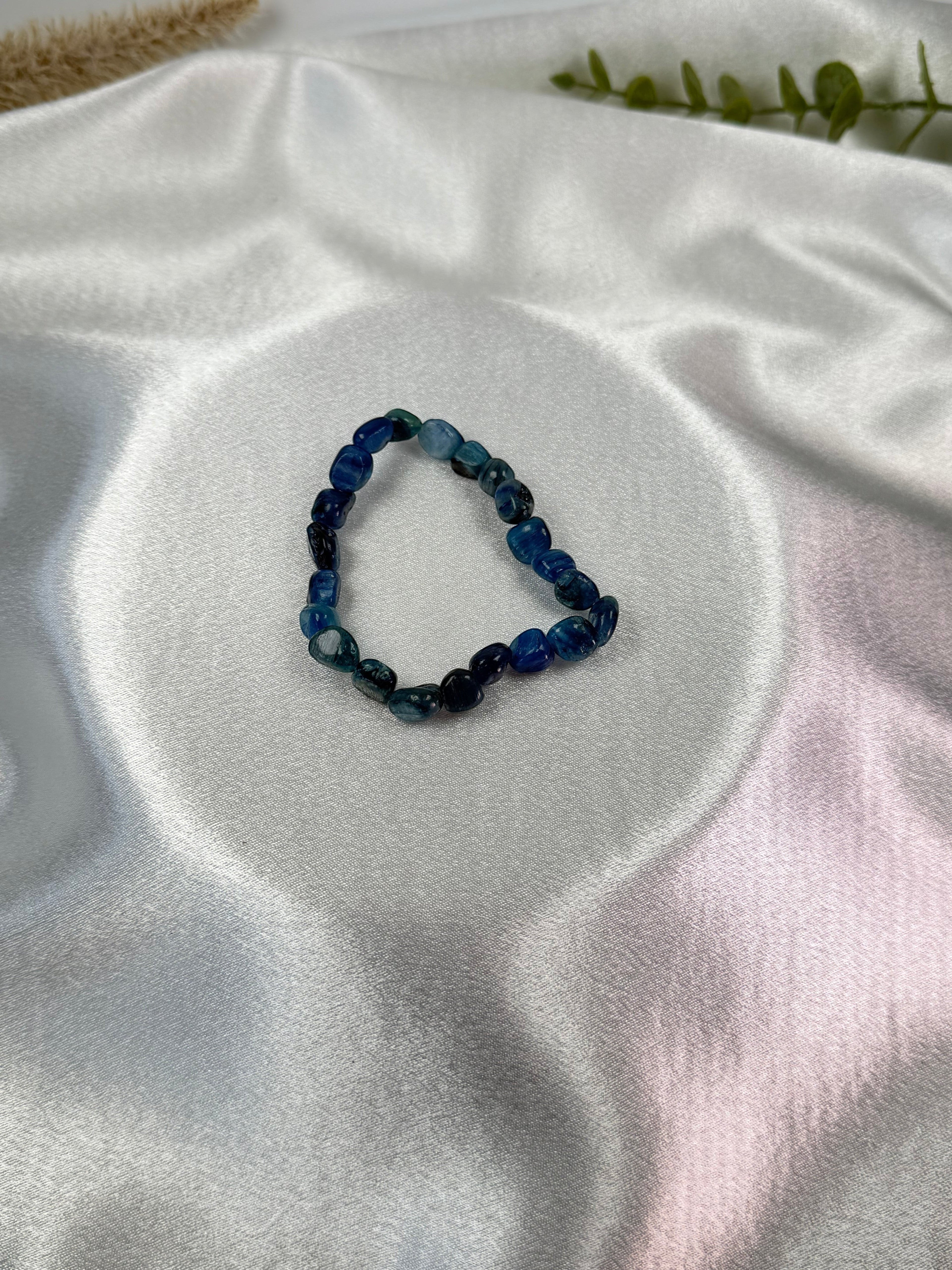 Treasured Energies polished blue kyanite gemstone bead stretch bracelet on a white satin fabric background