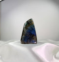 Treasured Energies large polished Labradorite freeform crystal with vibrant blue labradorescence on a white fabric base.