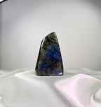 Treasured Energies large polished Labradorite freeform crystal with vibrant blue labradorescence on a white fabric base.