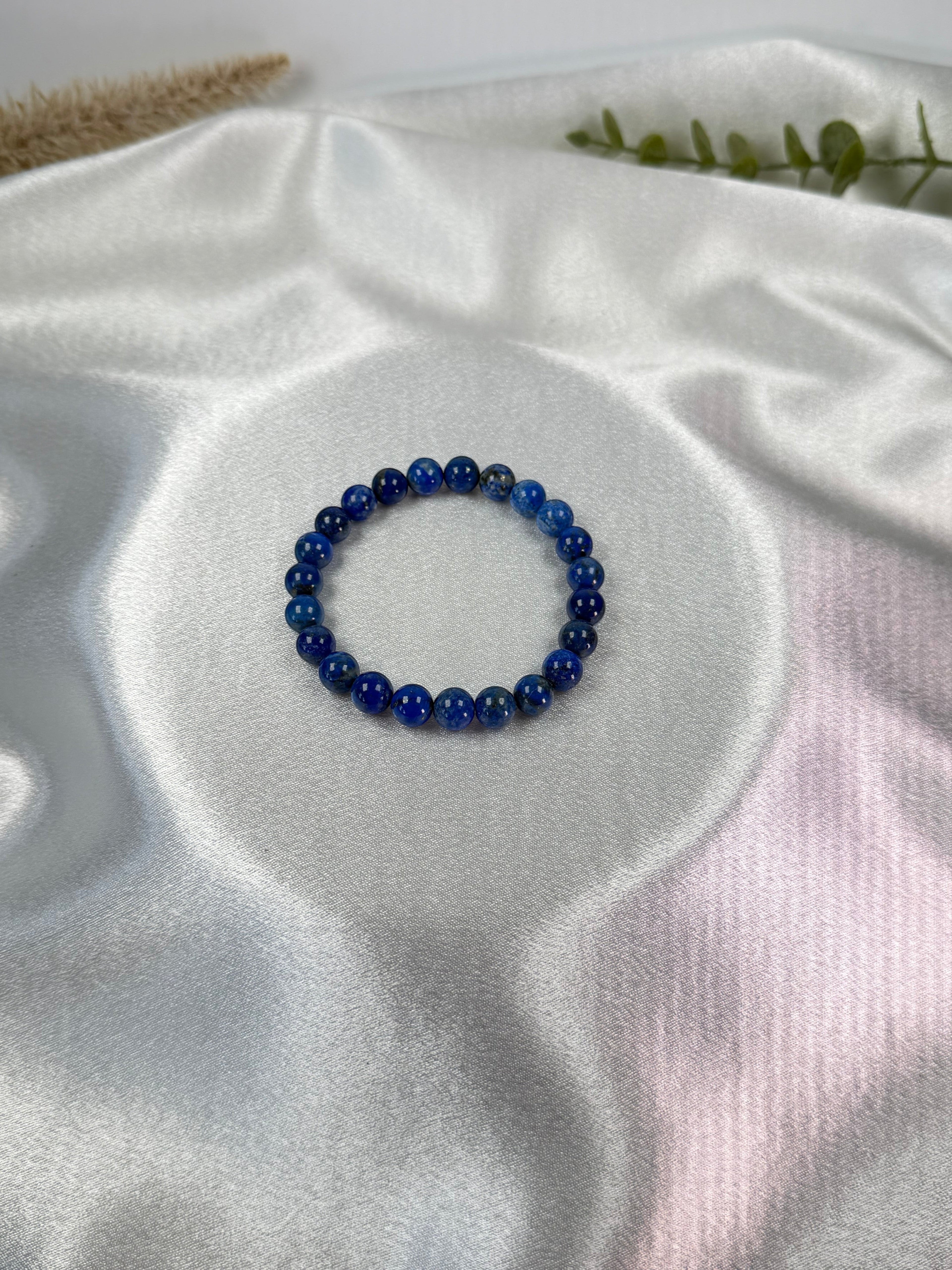 Treasured Energies natural lapis lazuli beaded elastic bracelet on a white satin background