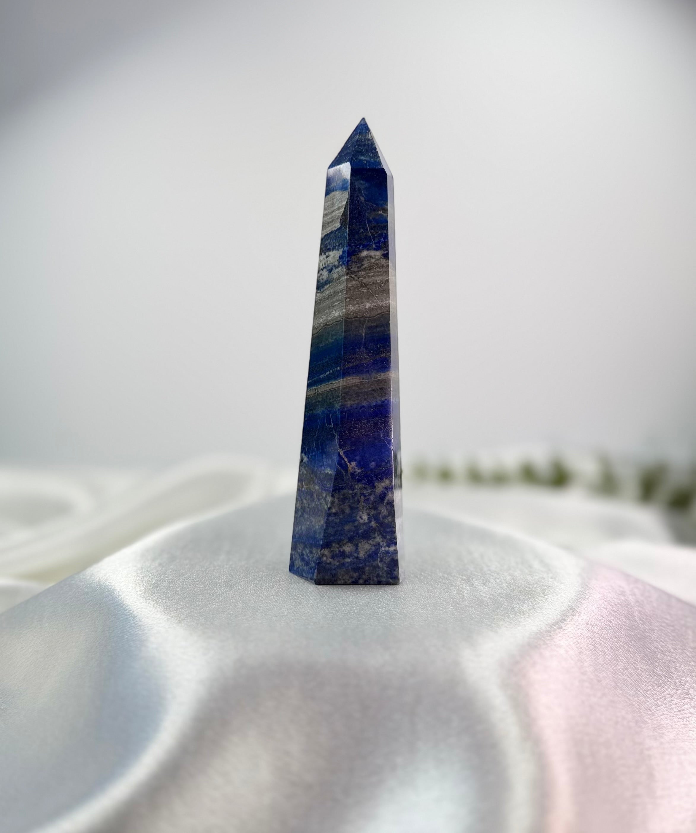 Treasured Energies deep blue Lapis Lazuli crystal tower with natural pyrite and calcite inclusions on white silk.