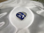Treasured Energies polished Lapis Lazuli heart crystal with deep blue, white, and gold tones on white satin fabric.