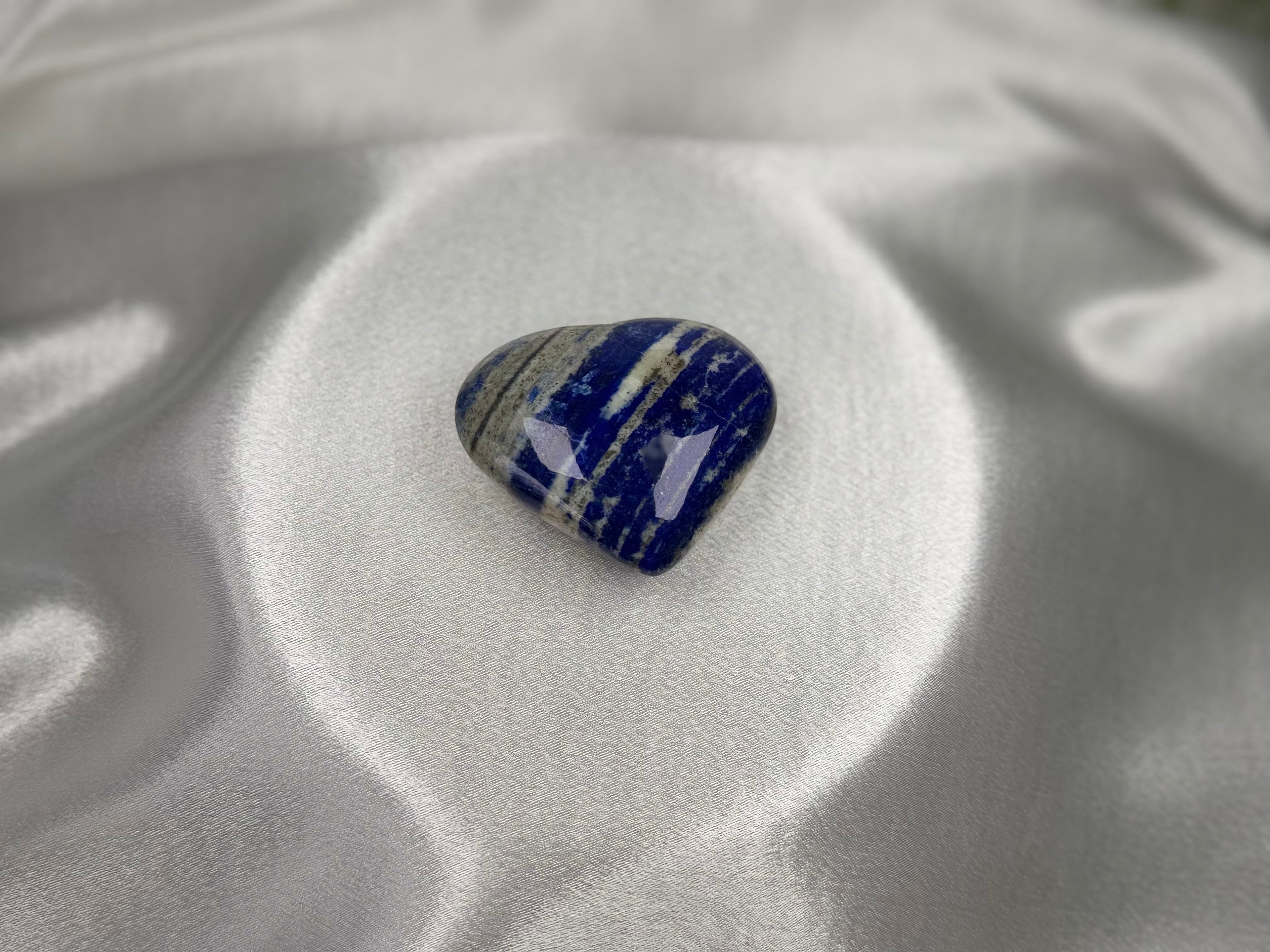 Treasured Energies polished Lapis Lazuli heart crystal with deep blue, white, and gold pyrite inclusions on silk.
