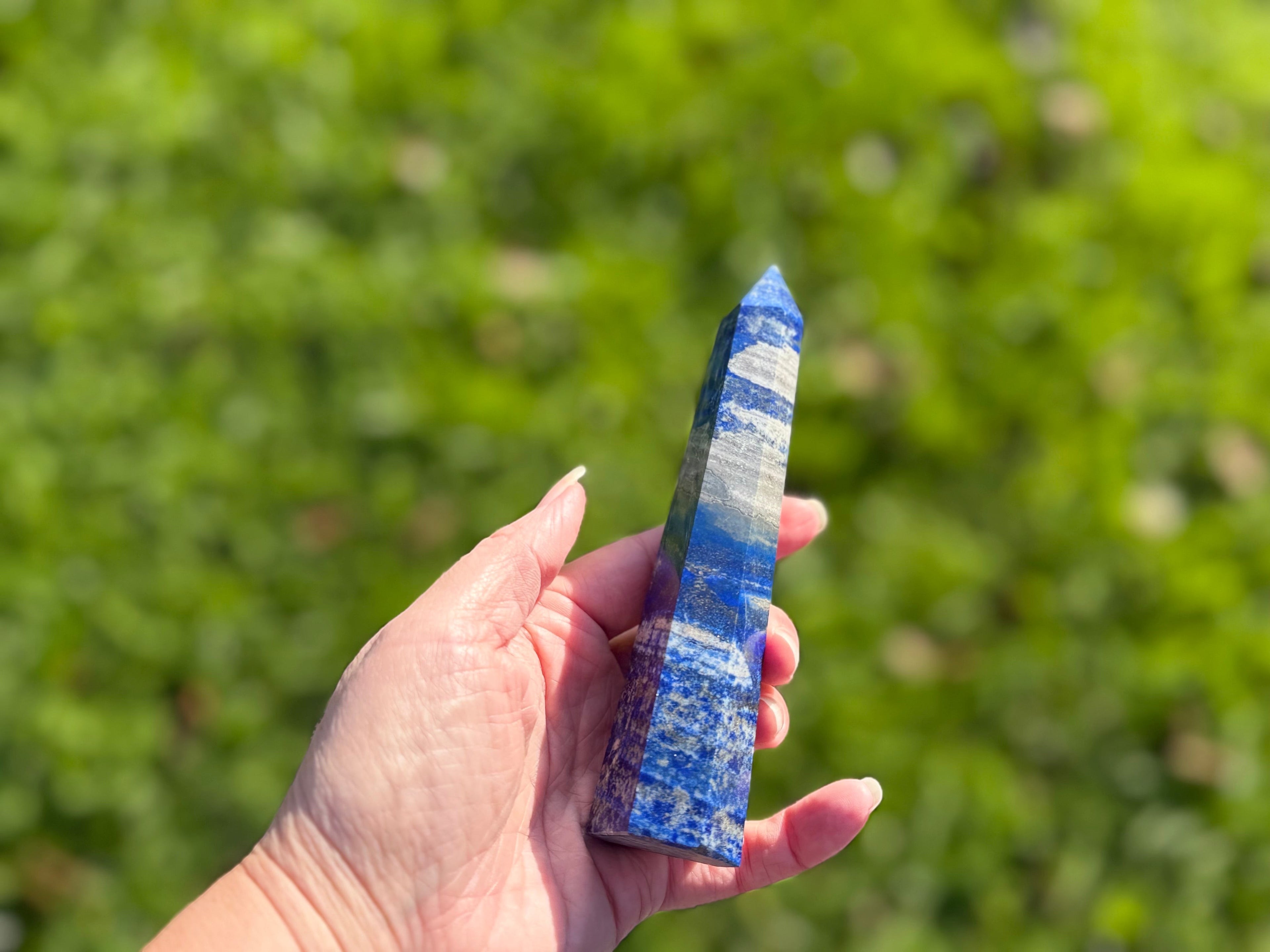 Treasured Energies Lapis Lazuli crystal tower held in hand, featuring deep blue stone with white calcite and gold pyrite.