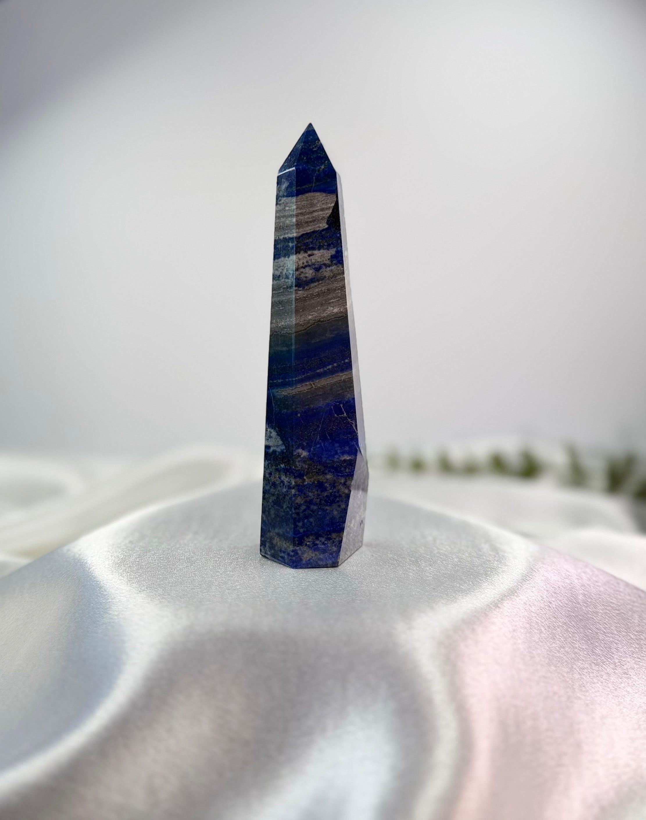 Treasured Energies Lapis Lazuli crystal tower with deep blue tones, golden pyrite, and white calcite on satin fabric.