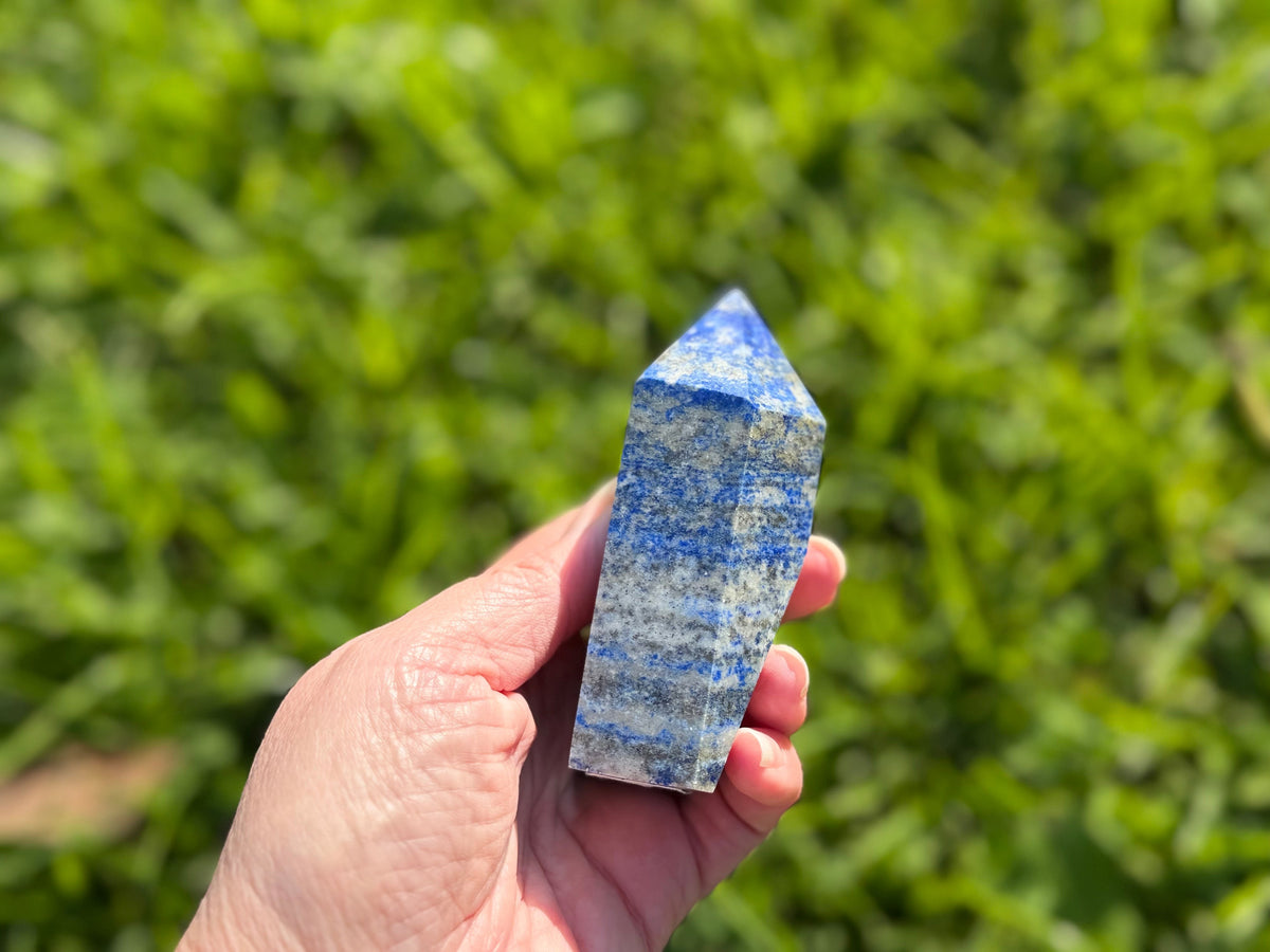 Treasured Energies medium Lapis Lazuli crystal tower held in hand, featuring deep blue stone with white calcite veins.