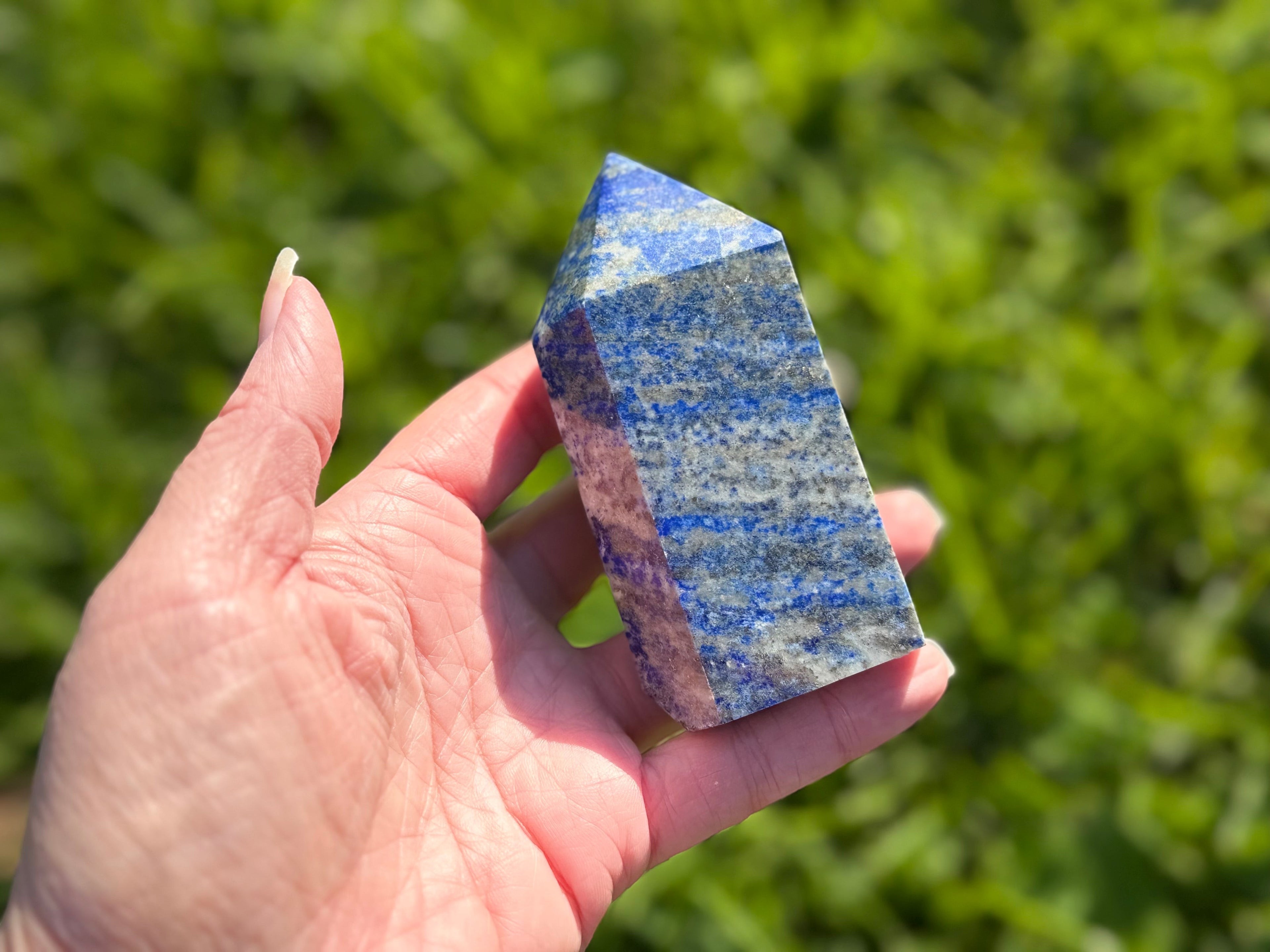 Treasured Energies medium Lapis Lazuli crystal tower held in hand with deep blue colour and natural pyrite inclusions