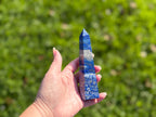 Treasured Energies Lapis Lazuli crystal tower held in hand, showing deep blue stone with golden pyrite and white calcite.