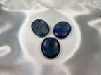 Treasured Energies Lapis Lazuli worry stones with deep blue colour and gold pyrite flecks on a white satin background