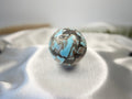 Treasured Energies polished Larimar crystal sphere with blue and brown patterns on a white satin background