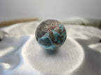 Treasured Energies Larimar crystal sphere with blue and grey oceanic patterns on a white satin background